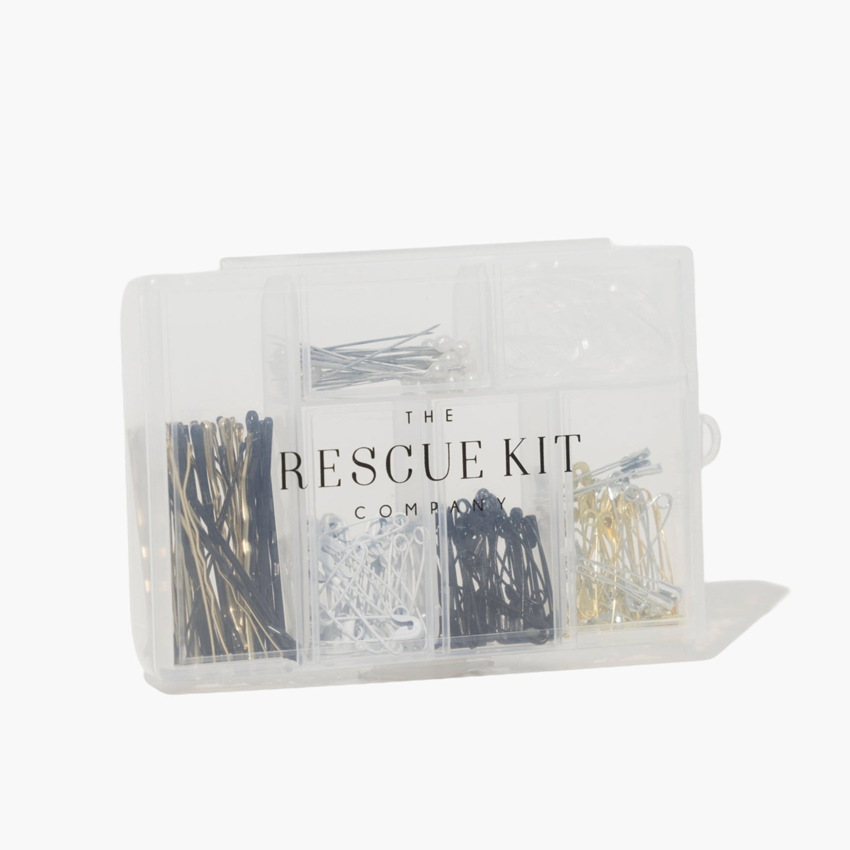 The Rescue Kit Company hair and pin kit, neatly organized in a clear case with assorted bobby pins, safety pins, pearl pins, and elastics in various colors.