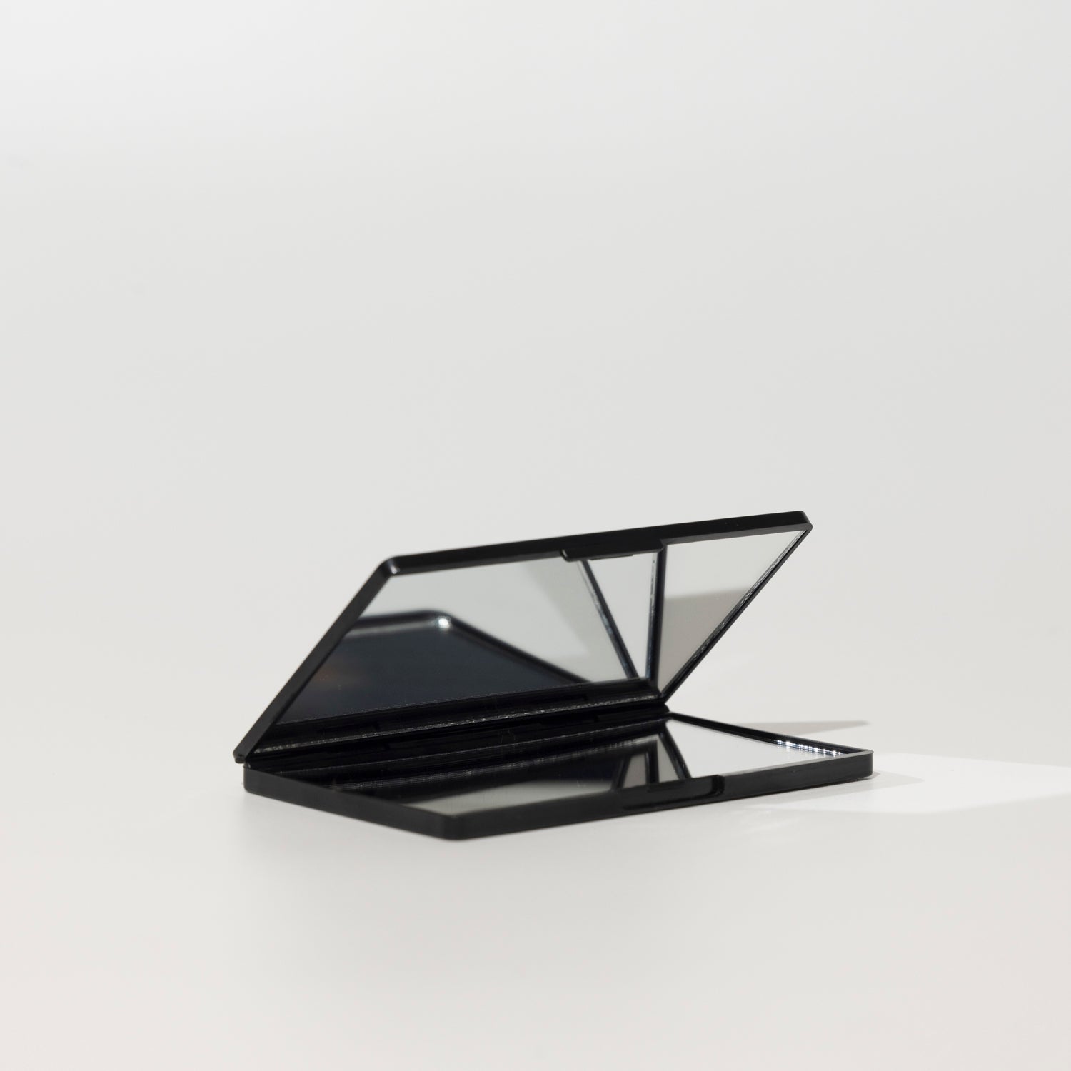 Open black foldable compact mirror from The Rescue Kit Company, shown with multiple reflective panels for versatile use and touch-ups on the go.