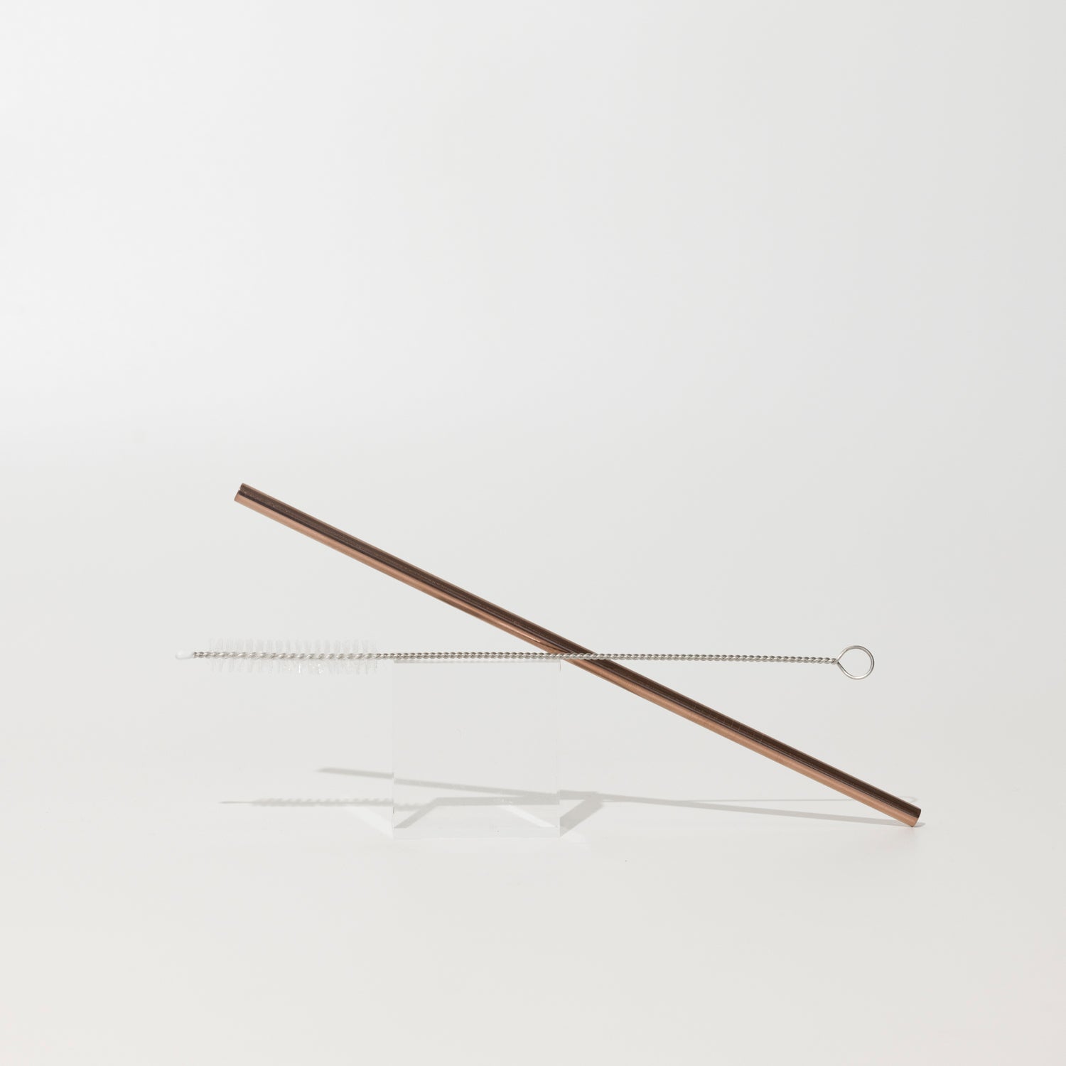 Reusable rose gold metal straw with cleaning brush.