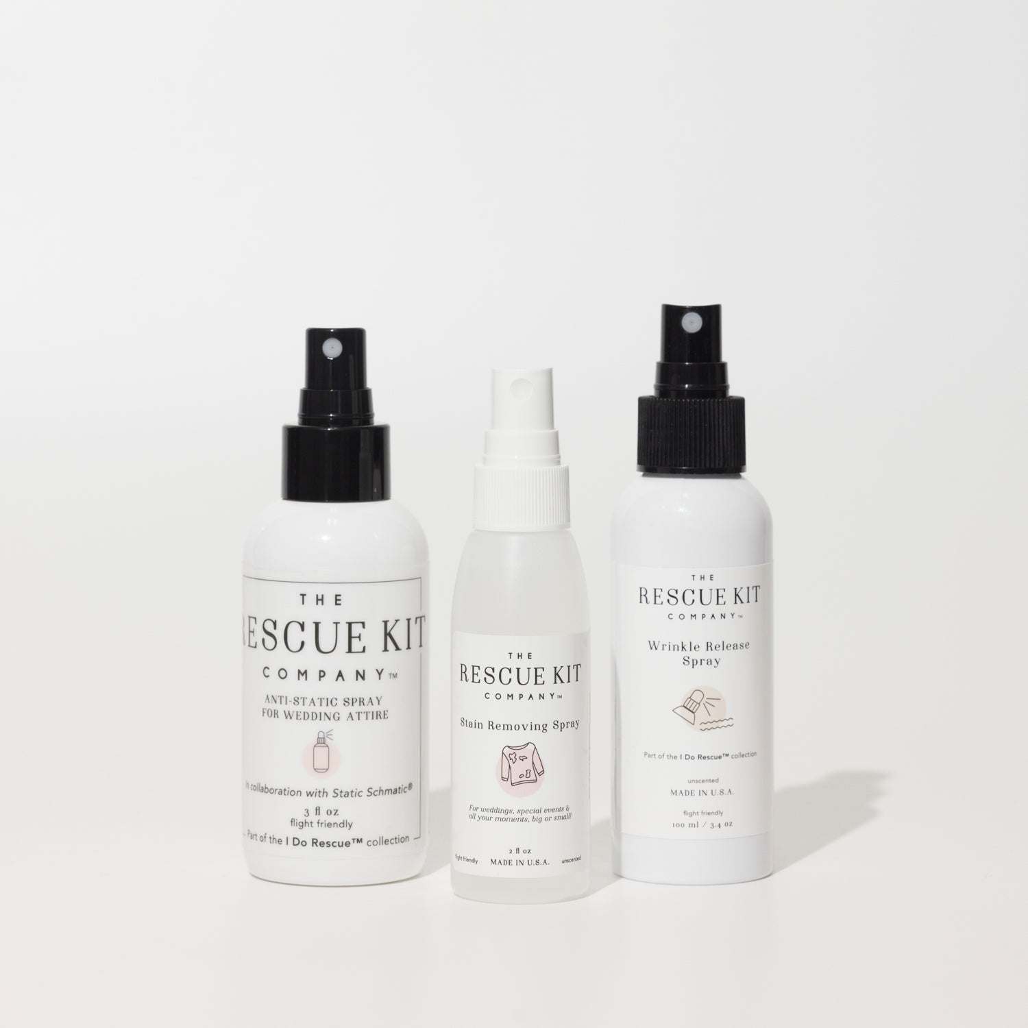 The Spray Trio by The Rescue Kit Company, white bottles, black tops. From left to right: Anti-Static Spray, Stain Removing Spray, and Wrinkle Release Spray, with protective caps removed.