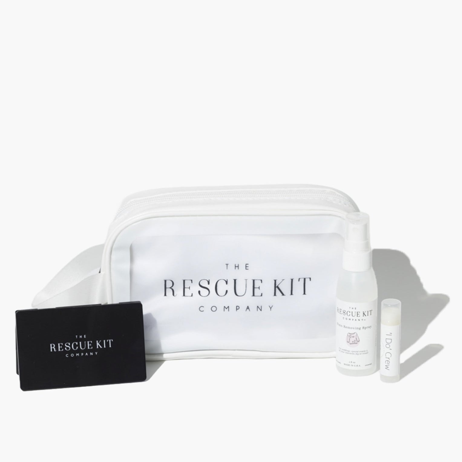The 'I Do' Crew Kit by The Rescue Kit Company. White cosmetic bag with black compact mirror, stain removing spray, and lip balm shown outside the bag.