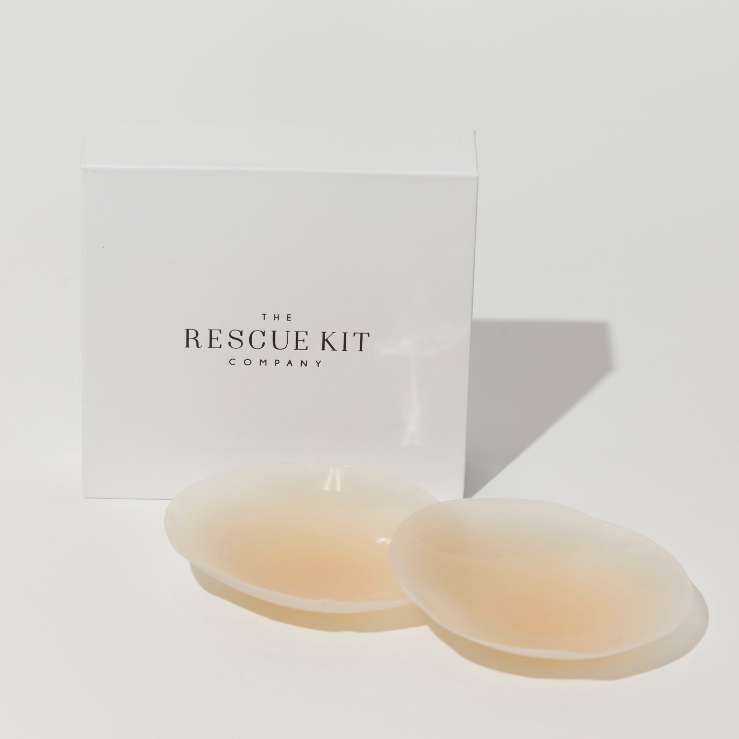 Silicone pasties by The Rescue Kit Company. Two pasties, light skin tone color, outside their white custom packaging box.
