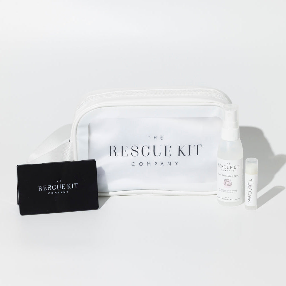 The 'I Do' Crew Kit by The Rescue Kit Company. White cosmetic bag with black compact mirror, stain removing spray, and lip balm shown outside the bag.