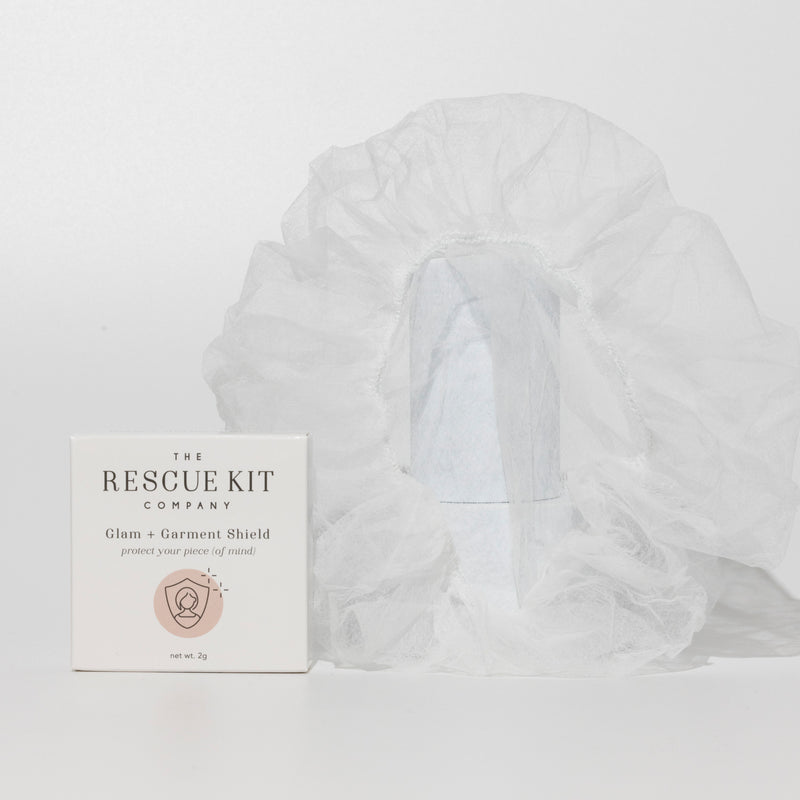 Exterior box of the Glam + Garment Shield by The Rescue Kit Company. White box, pink icon. Glam + Garment Shield pictured to the right of the box.