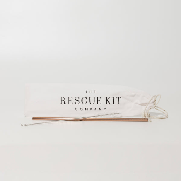 Reusable rose gold metal straw with cleaning brush, displayed in front of a white drawstring pouch featuring The Rescue Kit Company logo.