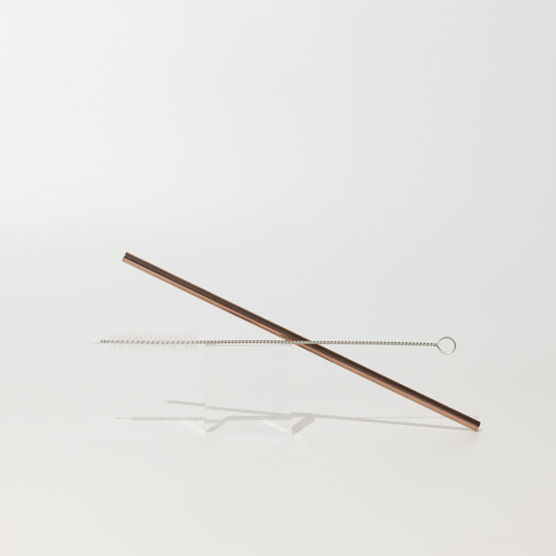 Reusable rose gold metal straw with cleaning brush.