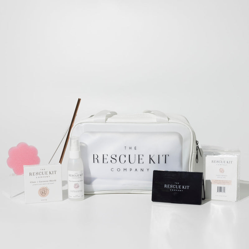 The Classic Bride Kit by The Rescue Kit Company, featuring a medium white cosmetic bag, stain removing spray, deodorant sponge, glam + garment shield, mini tissues, reusable straw, and black compact mirror.