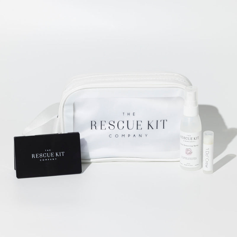 The 'I Do' Crew Kit by The Rescue Kit Company. White cosmetic bag with black compact mirror, stain removing spray, and lip balm shown outside the bag.