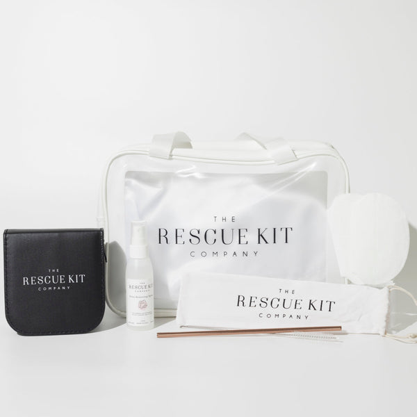 The Rescue Kit Company's Photo Shoot Kit, featuring a white cosmetic bag, stain removing spray, black leather sewing kit, underarm sweat pads, and reusable metal straw with cleaning brush in branded pouch.