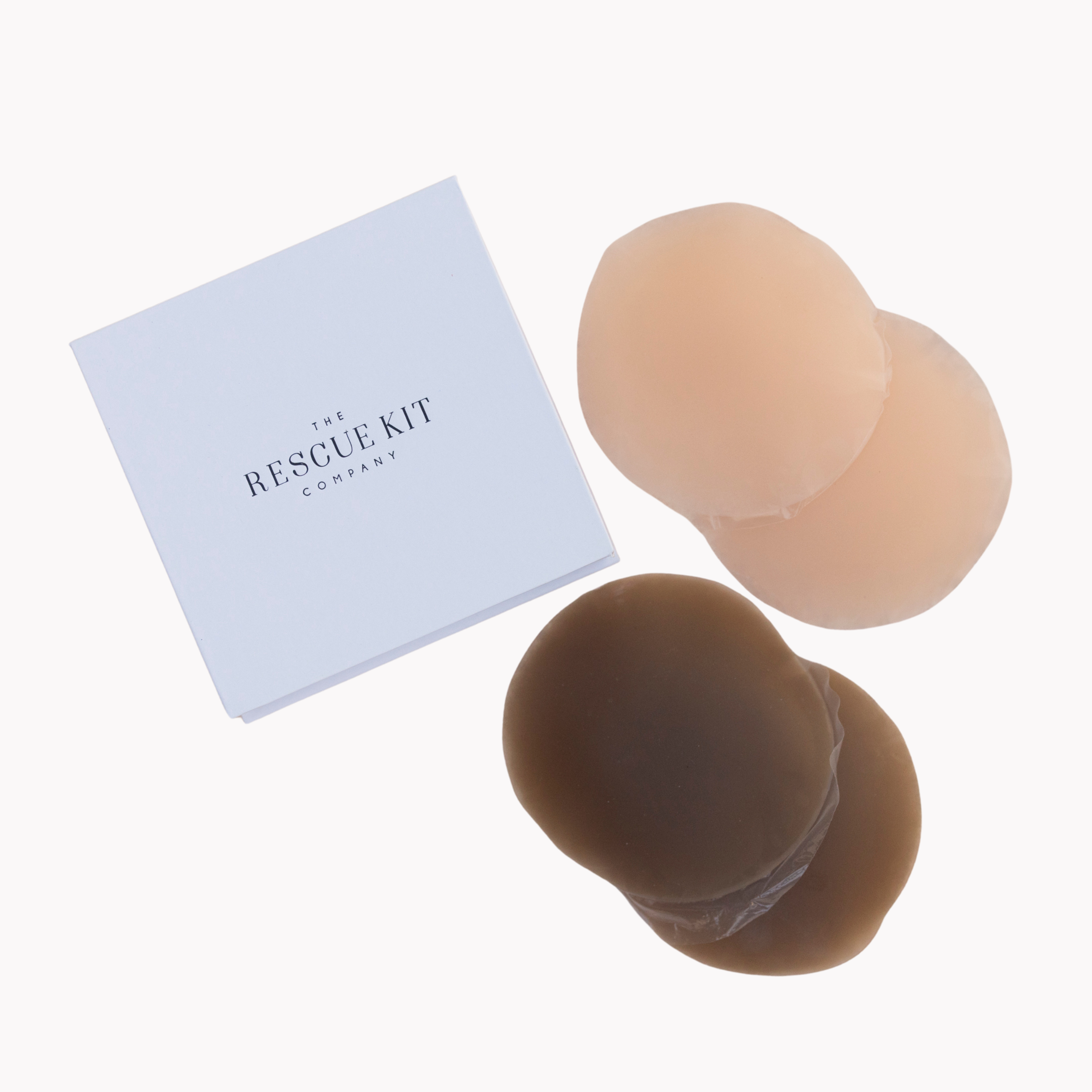 Silicone pasties by The Rescue Kit Company. Four pasties, light and dark skin tone color, outside their white custom packaging box.